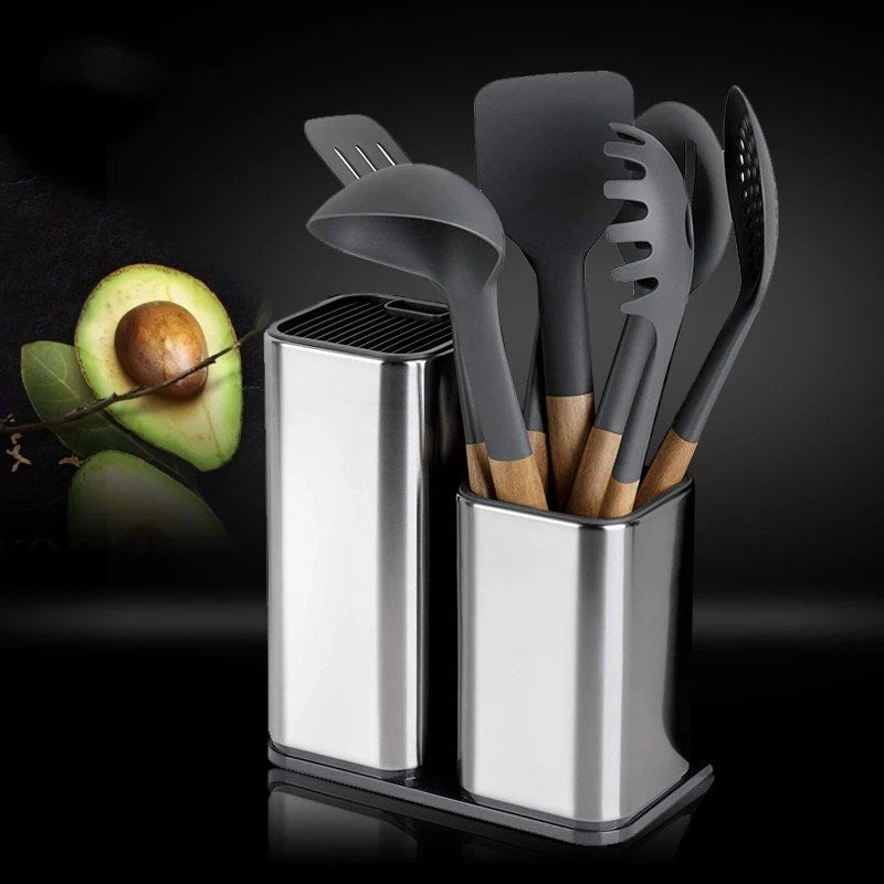 Set of gray kitchen utensils in a metal holder with an avocado on a dark background